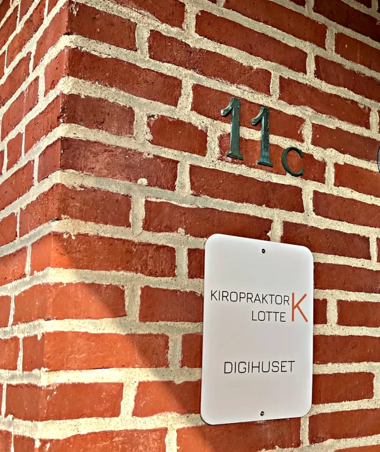 Klinikskiltet for Kiropraktor Lotte K og husnummer 11C på murstensvæggen ved indgangen, Sølstedgårdvej i Løgumkloster