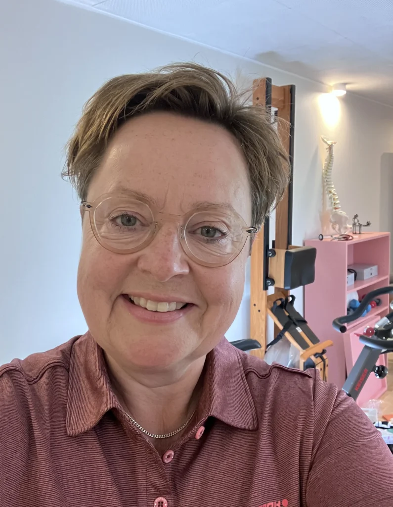Lotte Krogh, autoriseret kiropraktor, i klinikken i Løgumkloster med træningsudstyr i baggrunden